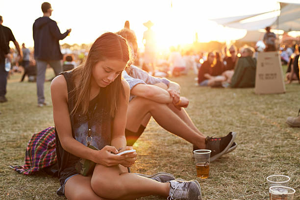 young woman tjecking smartphone at festival - concert stock pictures, royalty-free photos & images