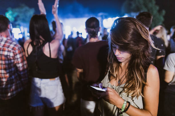 young woman using cell phone on music concert by night. - concert stock pictures, royalty-free photos & images
