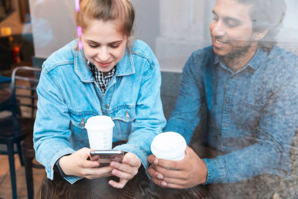 young woman using smartphone in a coffee shop while her boyfriend watching her - junk food stock pictures, royalty-free photos & images