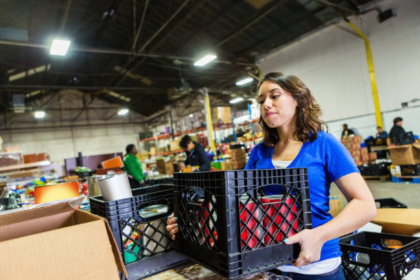 young woman volunteering to organize donations in large food bank - food stock pictures, royalty-free photos & images