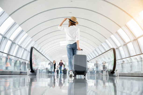 young woman wearing casual clothes and walking in the airport hall - travel photos et images de collection