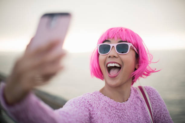young woman with pink hair taking a selfie - hairstyle stock pictures, royalty-free photos & images