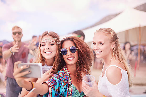 young women posing for selfie at music festival - concert stockfoto's en -beelden