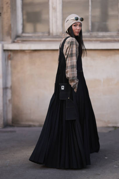 Yoyo Cao seen wearing a Sacai X Carhartt denim long jumpsuit dress, grey hat, Celine black sunglasses and a brown checkered blouse outside Sacai show...
