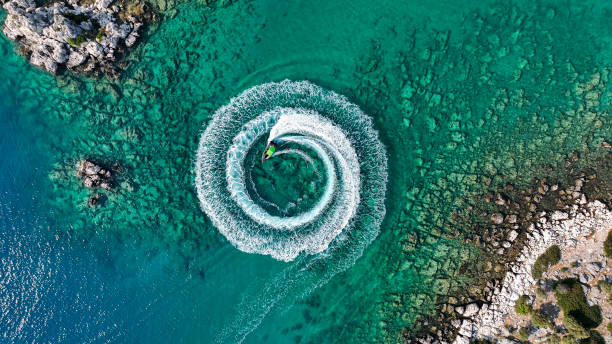 zoom out amazing aerial view of man driving a personal watercraft in the ocean creating a straight down circular pattern,amazing summer background, water color and beautiful bright clear turquoise adventure day on tropical be