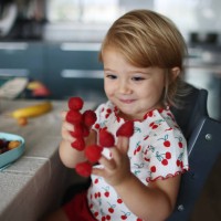 a baby girl playing with raspberries on her fingers, in the kitchen - food stock pictures, royalty-free photos & images