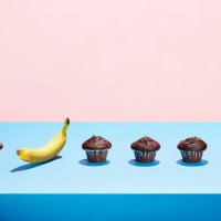 a banana in a row of chocolate cupcakes - junk food stock pictures, royalty-free photos & images