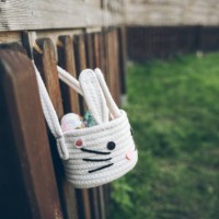a basket of easter eggs on a fence on a lawn - garden decoration stock pictures, royalty-free photos & images