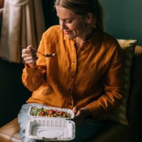 a beautiful blonde female sitting in her living room eating some healthy food - junk food stock pictures, royalty-free photos & images