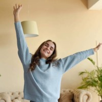 a beautiful girl in a blue sweater is stretching in the room. - fashion stock pictures, royalty-free photos & images