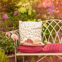 a beautiful summer cast iron garden chair with cushions and a summer hat, shabby chic scene - garden decoration stock pictures, royalty-free photos & images