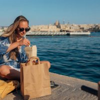 a beautiful woman enjoys eating noodles and relaxing by the sea - junk food stock pictures, royalty-free photos & images
