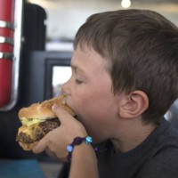 a child eats a burger - junk food stock pictures, royalty-free photos & images