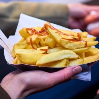 a close-up of a hand holding tasty takeaway chips at night with ketchup - junk food stock pictures, royalty-free photos & images