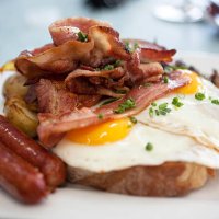 a closeup of eggs, bacon, ham, and sausage on top of toast - junk food stock pictures, royalty-free photos & images