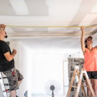 a couple undergoing renovations measure the distances to place the spotlights on the ceiling during an electrical renovation... - home decoration stock pictures, royalty-free photos & images