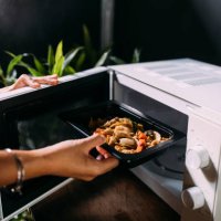 a cropped photo of an anonymous caucasian female heating food in the oven - junk food stock pictures, royalty-free photos & images