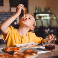 a cute girl eats pizza with an appetite, stretching the cheese. - junk food stock pictures, royalty-free photos & images