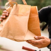 a delivery man is using a bike to transport food in the city - junk food stock pictures, royalty-free photos & images