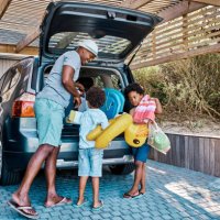 a family packing the car to leave for summer vacation. a happy african american father and his two cute little sons preparing the luggage in his vehicle to go on a road trip, ready for travel time - travel stock pictures, roy