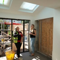 a female builder stands in a building site amongst a half finished renovation discussing the project with her client. - home decoration stock pictures, royalty-free photos & images