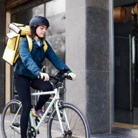 a female delivery person standing in front of a doorway. - junk food stock pictures, royalty-free photos & images
