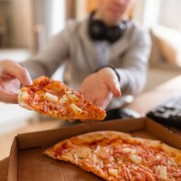 a gamer eating pizza out of the box, sitting in front of his computer - junk food stock pictures, royalty-free photos & images