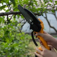 a gardener prunes trees with a light cordless chain saw. gardening. - garden decoration stockfoto's en -beelden