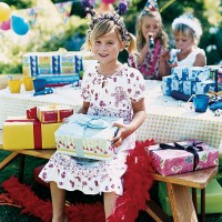 a girl at an open air birthday party, sitting at a table, holding a present - garden decoration stockfoto's en -beelden