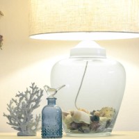 a glass lamp filled with shell illuminates some object at a beach house sideboard. - home decoration stock pictures, royalty-free photos & images