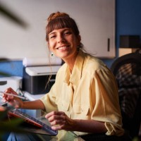 a graphic designer working from home with her digital tablet looking at the camera and smiling - home decoration stock pictures, royalty-free photos & images
