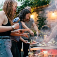 a group of friends helping themselves to food at a summer barbecue - food stockfoto's en -beelden
