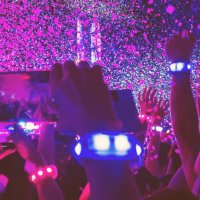 a group of people ecstatic with led bracelet recording with smartphone the concert with hands up, confetti and energy. - concert stock pictures, royalty-free photos & images