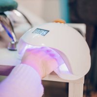 a hand inside a uv lamp for drying nail polish - nails art stock pictures, royalty-free photos & images