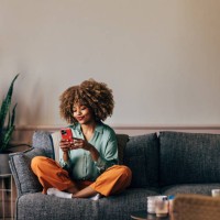 a happy beautiful woman texting on her mobile phone while relaxi - home decoration stock pictures, royalty-free photos & images