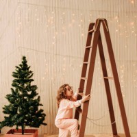 a little girl child in pajamas is playing standing near the stairs and the christmas tree in her children's room in a cozy house. innatesten winter holidays indoor - home decoration stock pictures, royalty-free photos & image