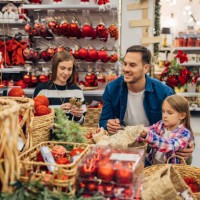 a little girl chooses christmas decorations with her parents. they look at the selection of decorations that are on display in the department store - home decoration stock pictures, royalty-free photos & images