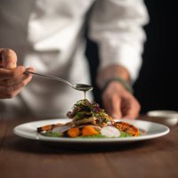 a male chef pouring sauce on meal - food stock pictures, royalty-free photos & images