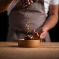 a male pastry chef pouring pistachios on profiteroles - food stock pictures, royalty-free photos & images