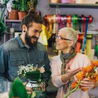 a man and a woman holding flower arrangements at a flower shop - garden decoration stock pictures, royalty-free photos & images