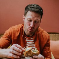 a man chews a large bite of a burger - junk food stock pictures, royalty-free photos & images