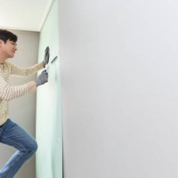 a man putting wallpaper on wall - home decoration stock pictures, royalty-free photos & images