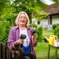 a mature woman plants flowers in her yard. a mature woman plants candles in her yard, uses the beautiful spring weather to decorate her garden around the house. - garden decoration stock pictures, royalty-free photos & images