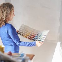 a mature woman studying a paint colour swatch - home decoration stockfoto's en -beelden