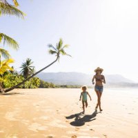 a mother and her daughter running down a palm tree scattered beach in costa rica. - travel stockfoto's en -beelden