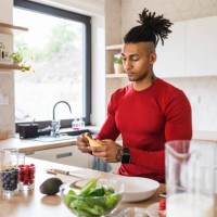 a portrait of fit mixed race man with dreadlocks in kitchen at home preparing healthy food. - food stockfoto's en -beelden