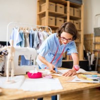 a portrait of young creative woman indoors making old clothes new and trendy. - fashion stock pictures, royalty-free photos & images