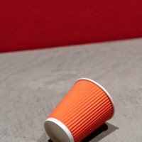 a red corrugated disposable paper coffee cup lying on a gray concrete table against a painted wall. takeaway, coffee to go. the concept of environmental pollution, recycling, recycling - junk food stock pictures, royalty-free