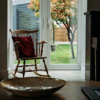 a rocking chair with a red velvet pillow by a large window and view of a beautiful garden - garden decoration stock pictures, royalty-free photos & images