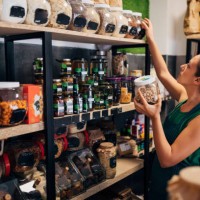 a saleswoman in an organic food store arranges jars of raw food on the shelf - food stock pictures, royalty-free photos & images